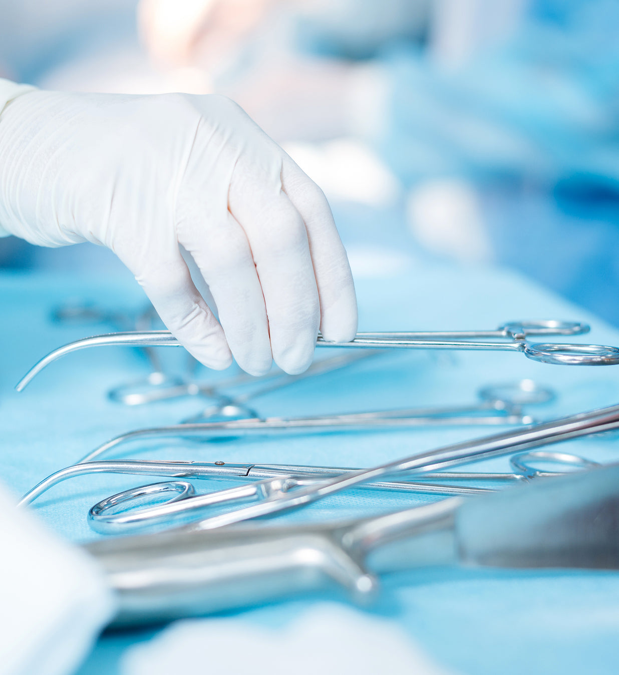 Hand wearing a white glove selecting surgical instruments