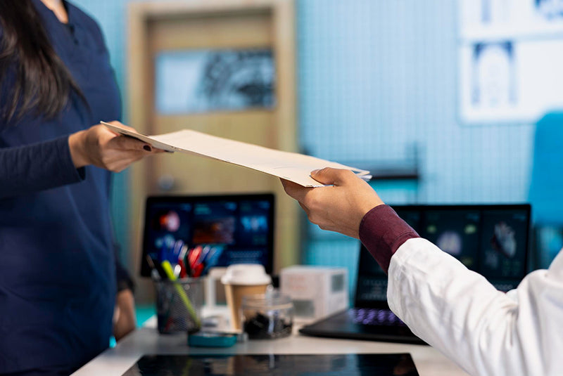Patient handing medical documents to doctor in clinic