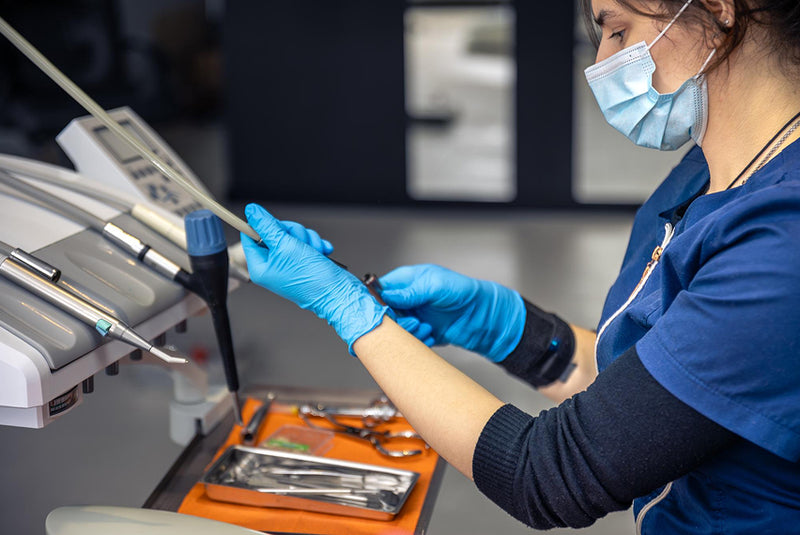 Healthcare professional wearing gloves and mask preparing and sterilizing surgical instruments