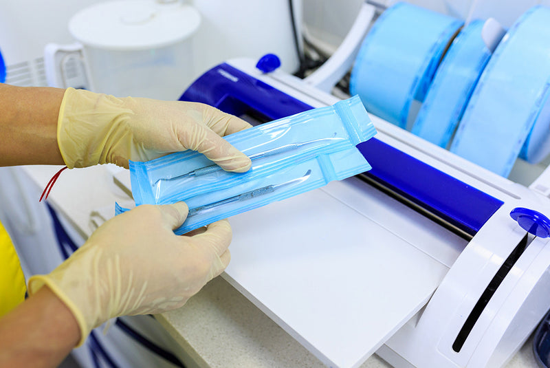 Healthcare worker sealing sterile medical instruments in packaging using heat sealer