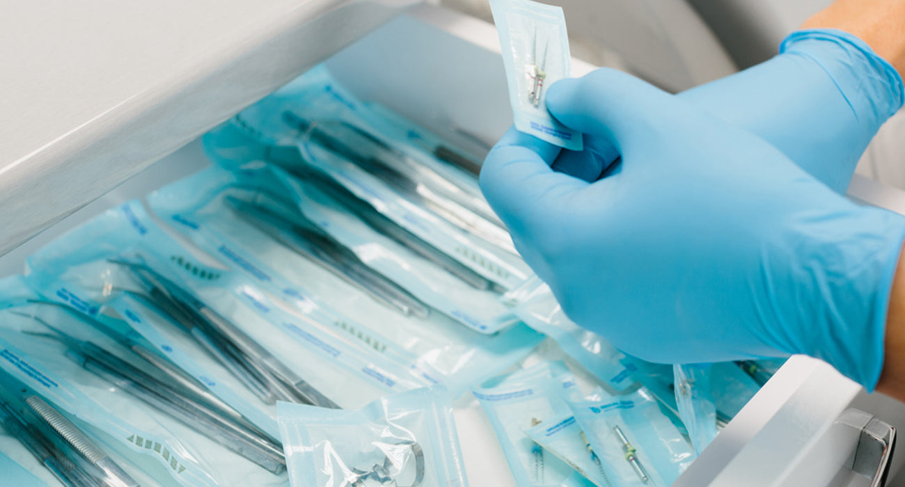 Person wearing blue gloves handling medical syringes in a sterile environment